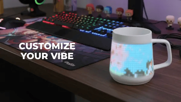 PixelMug on a gaming desk displaying colorful pixel animation with RGB keyboard in background