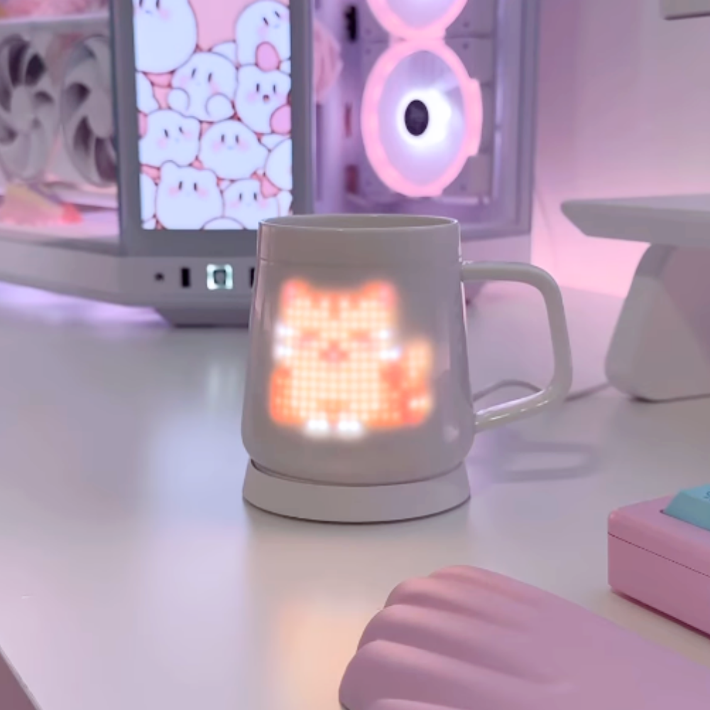 PixelMug P1 showing a glowing pixel cat on a pink aesthetic desk setup with pastel PC and accessories